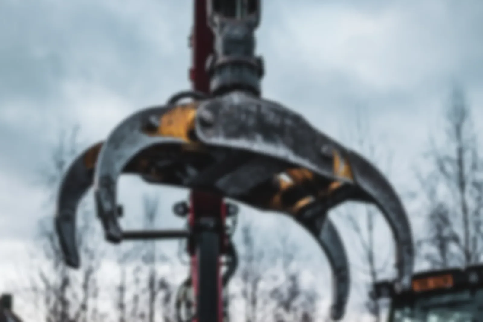 Drapák hydraulické ruky na nakládání dřeva proti zatažené obloze