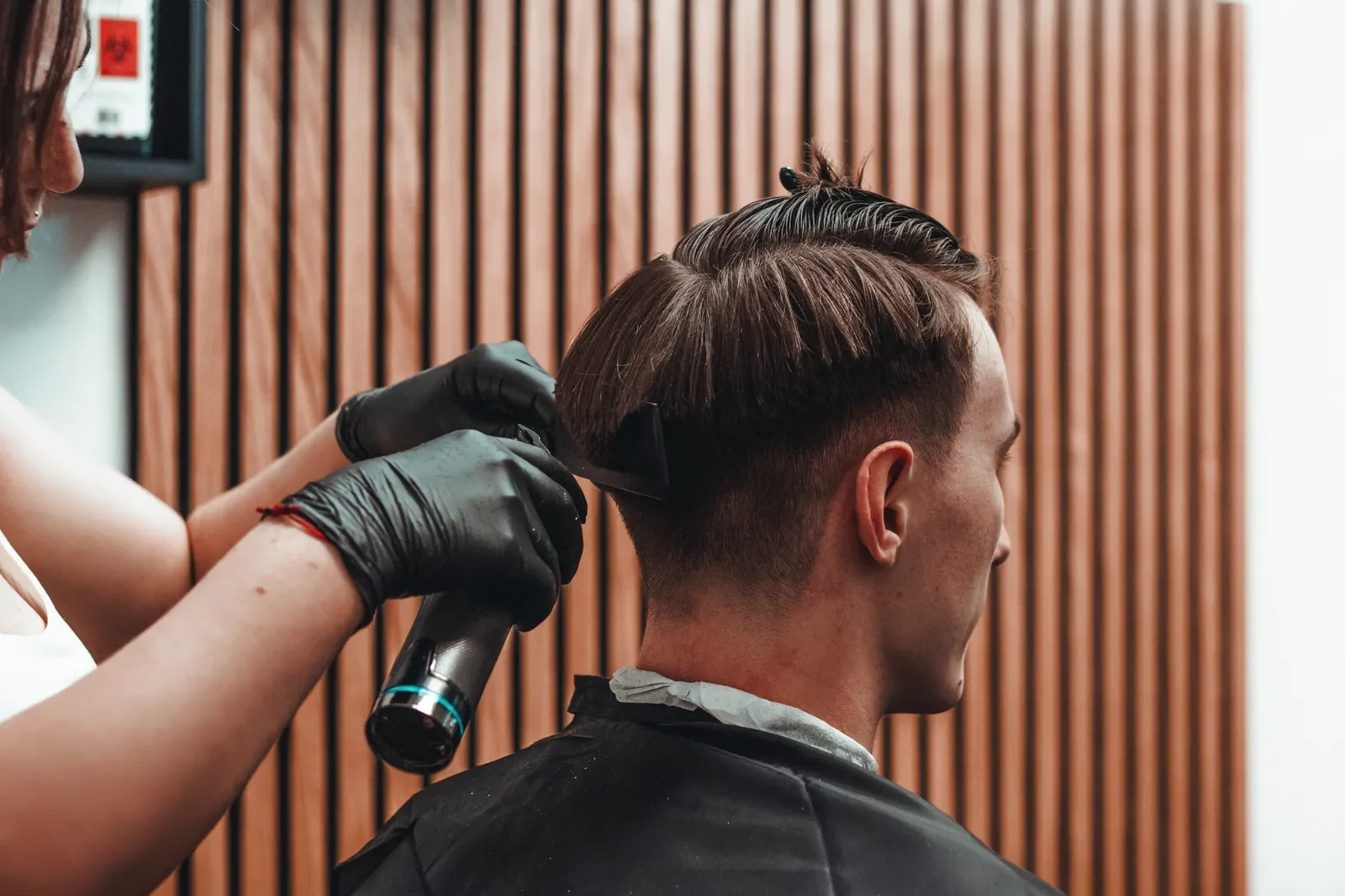 Holič v Medusa Barber upravuje vlasy zákazníka
